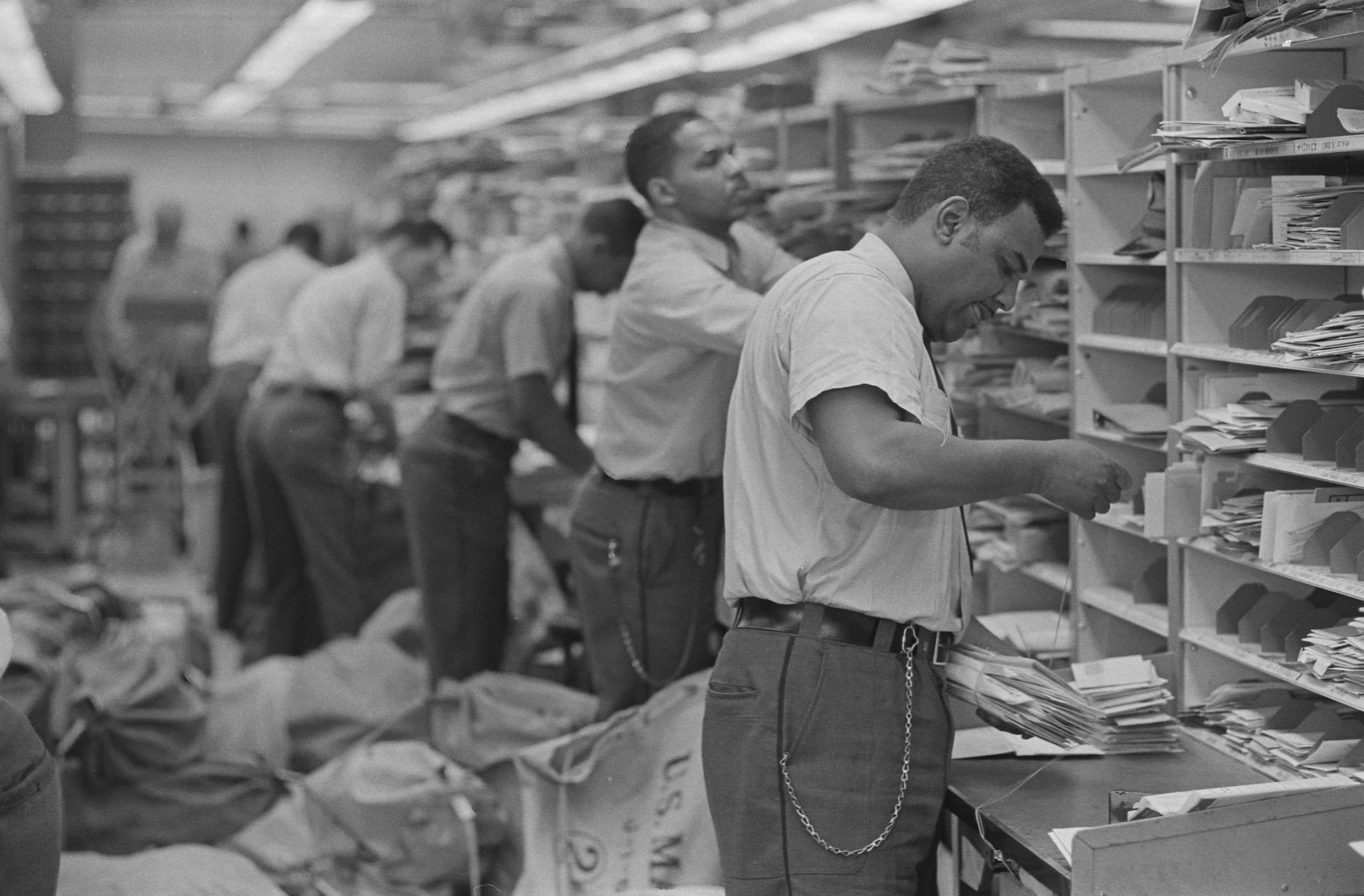 [African American postal employees sorting mail into cubby-holes]. By photographer Warren K. Leffler, 1966. Library of Congress Prints & Photographs Division. https://www.loc.gov/item/2011648799/