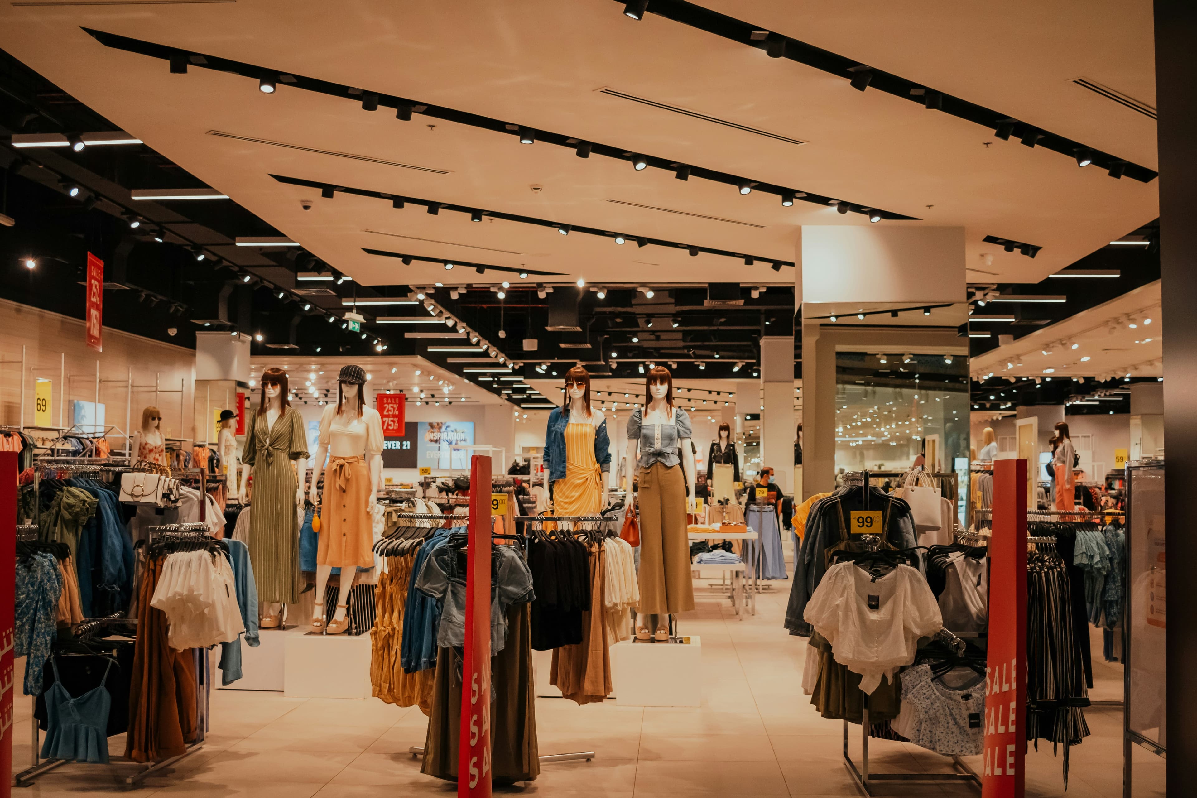 A retail shopping store with a lot of clothing and manikins