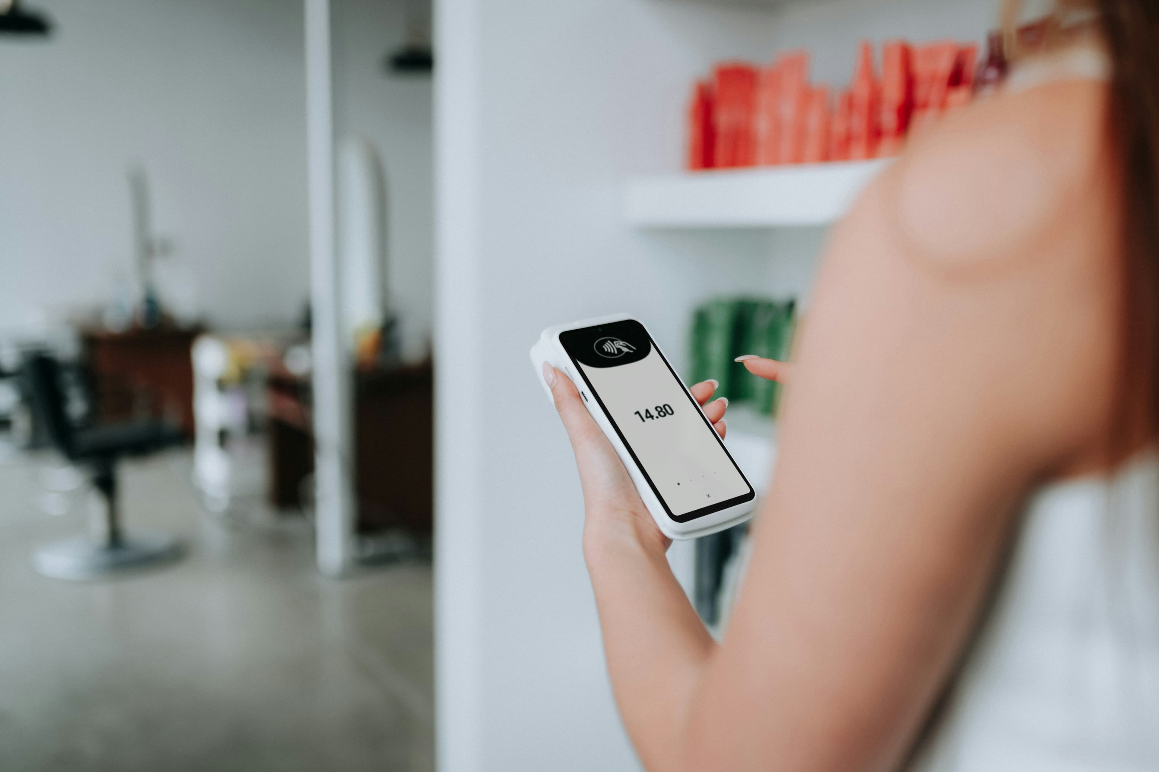 Minimalist shot of a client using a SumUp card reader surrounded by beauty products.