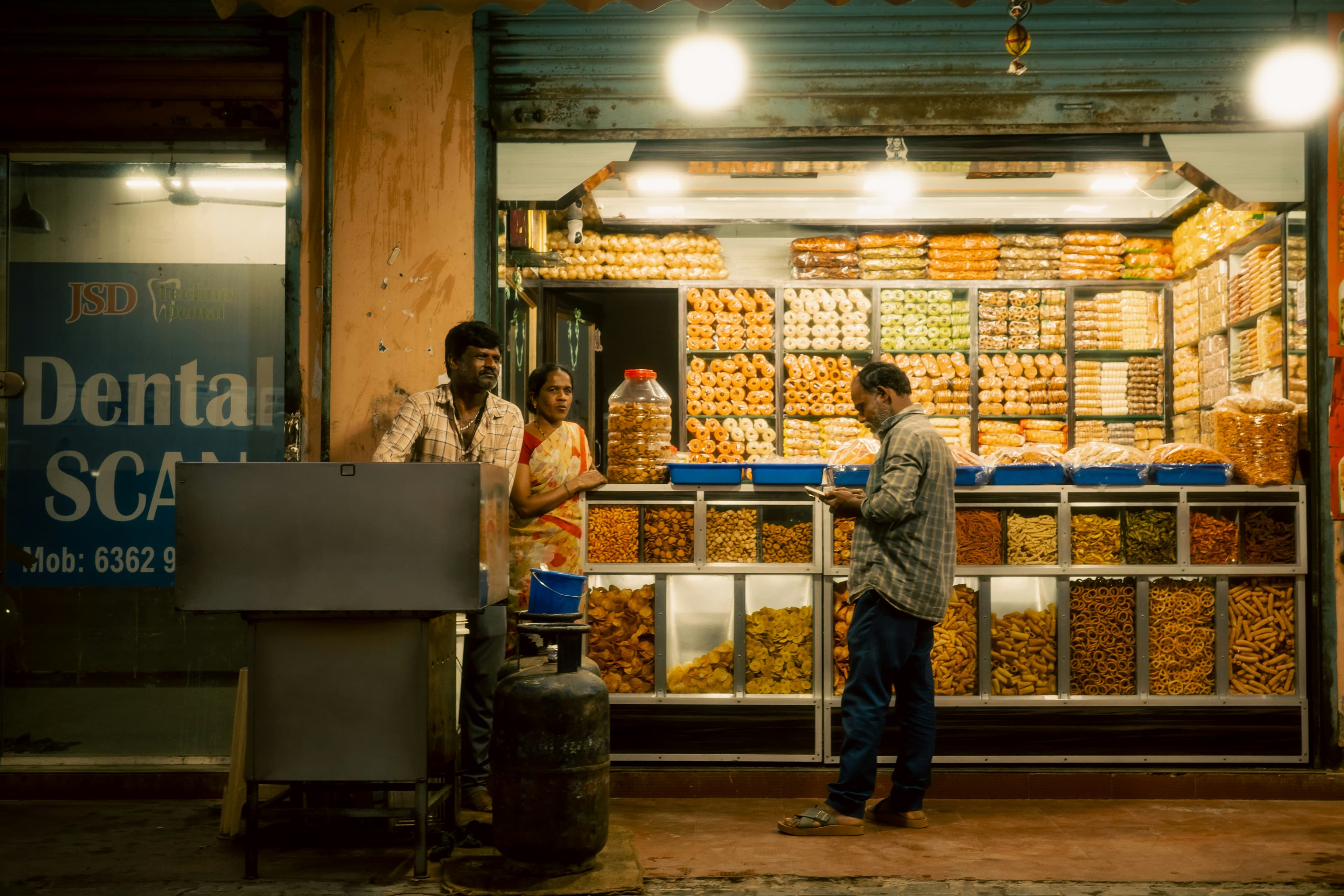 People at a brightly lit street food stall at night