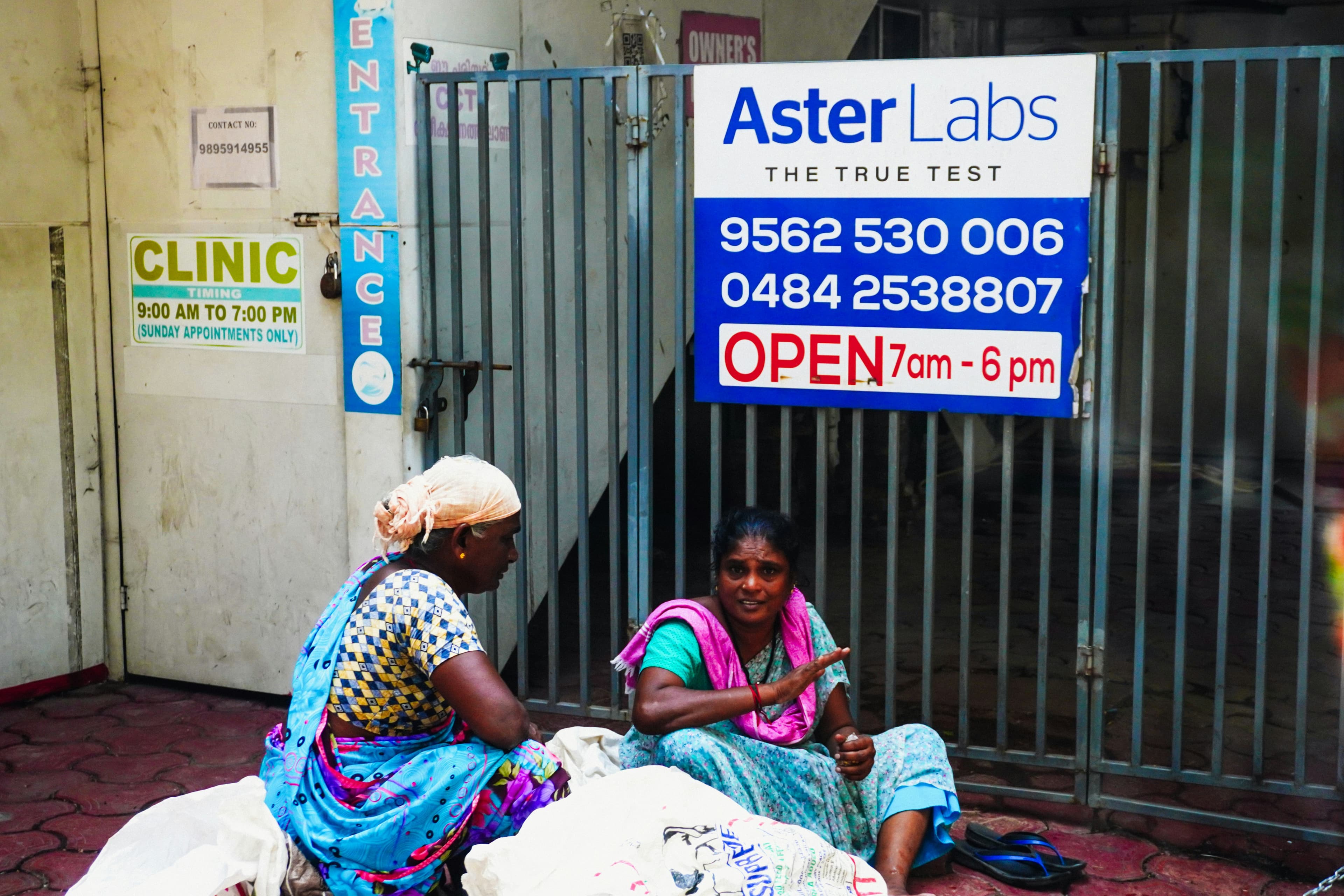 Two women sitting outside a clinic entrance.