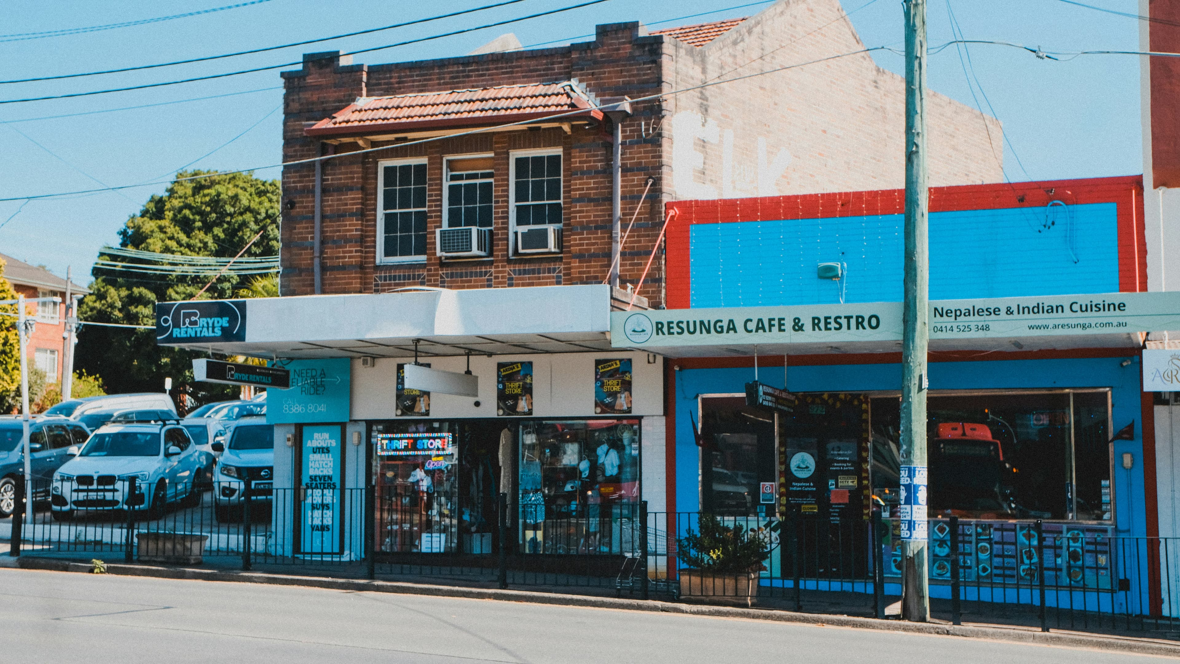 Old brick buildings and shops line a sunny street